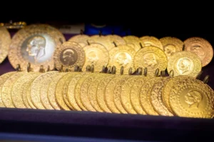 Rows of gold coin pendants with ornate patterned borders and portrait reliefs displayed on a dark velvet tray, representing jewellery and precious metals applications for laser engraving solutions