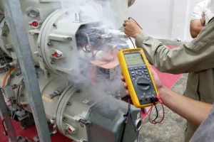 A technician holding a digital multimeter probes the wiring of grey electrical equipment as white smoke rises from it, representing automotive electronics applications for electronic fume extraction