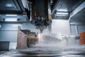 A CNC milling spindle cutting a finned aluminium part held on a rotary fixture, with coolant mist and metal chips filling the machine enclosure, representing precision components manufacturing applications for dust fume extractor solutions