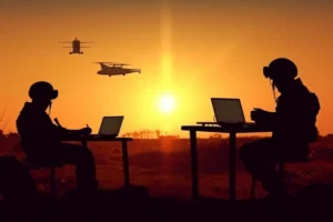 Silhouettes of two soldiers in helmets with headsets working on laptops at field tables at sunset, with two helicopters flying overhead, representing defence and secure communication applications for the CORX coherent optical receiver