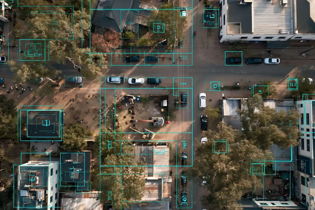Aerial view of a street intersection with cars, buildings and trees, overlaid with cyan detection boxes, representing coherent LiDAR applications for the narrow linewidth tunable laser